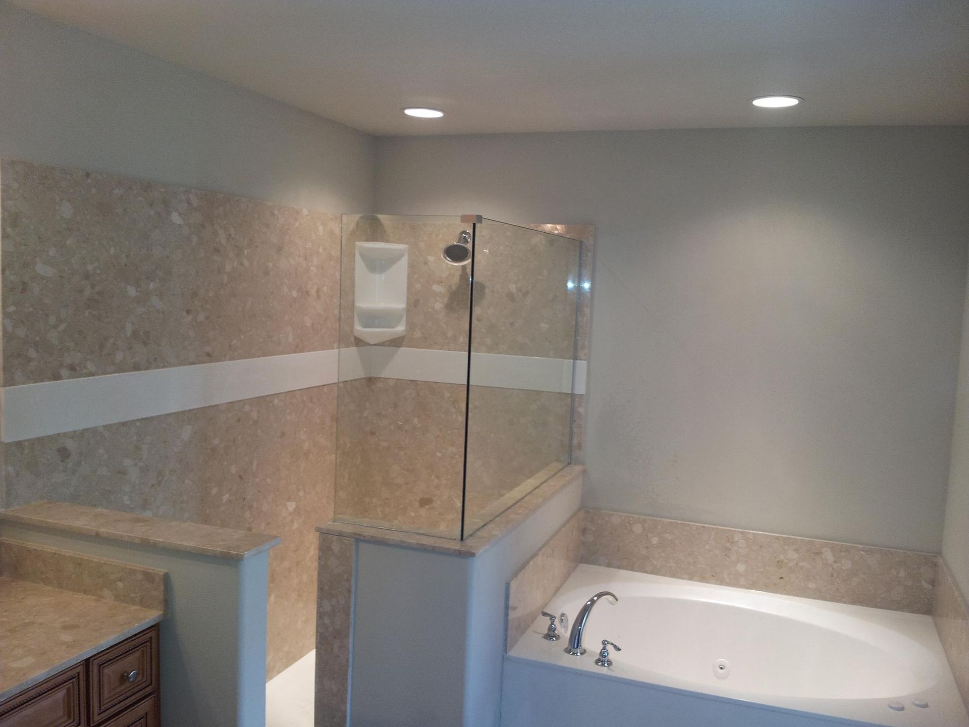 Bathroom with beige tiled shower and tub, glass enclosure, recessed lighting.