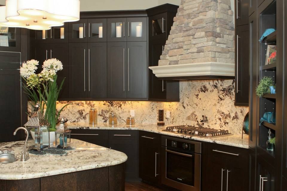 Dark wood kitchen with granite countertops and stone range hood.