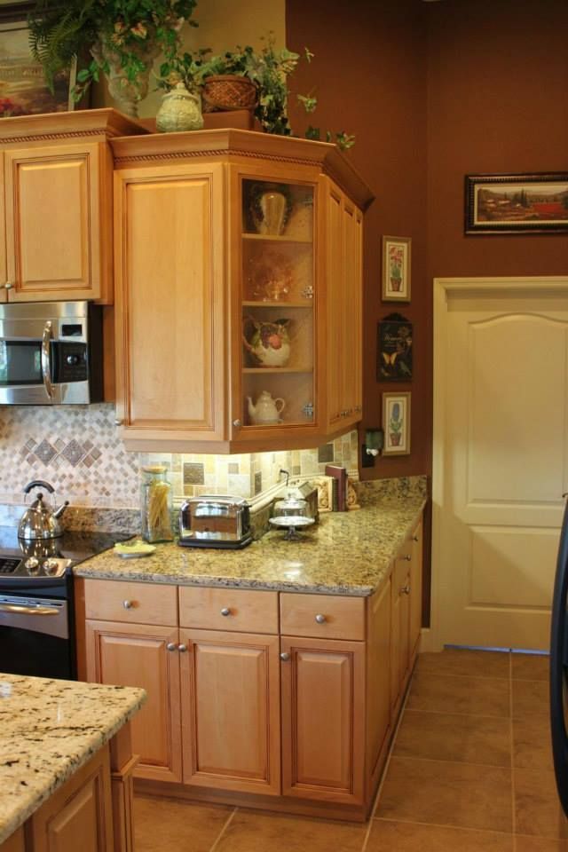 Kitchen with light wood cabinets, granite countertops, and decorative items.