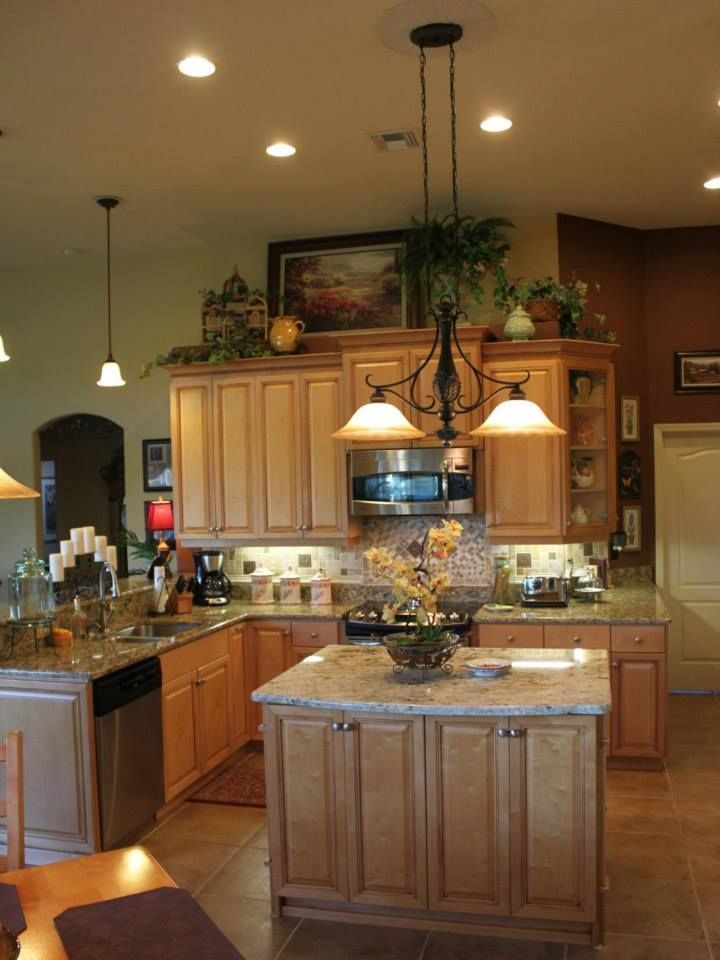 Kitchen with light wood cabinets, granite countertops, and island with a chandelier.