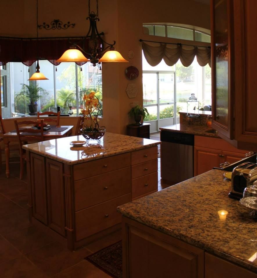 Kitchen with an island, granite countertops, dining table, and large window.