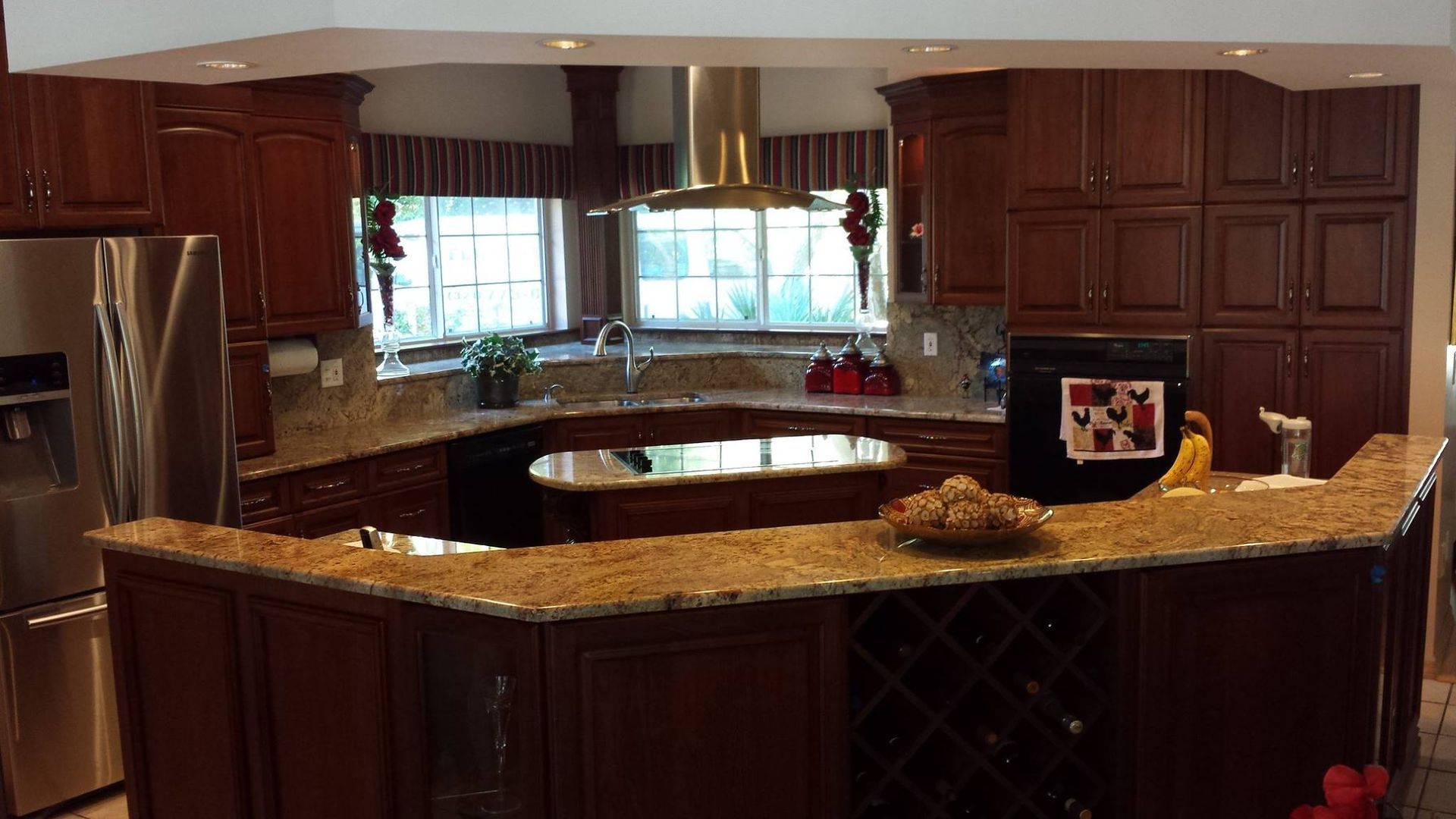 A kitchen with dark wood cabinets, granite countertops, and stainless steel appliances.