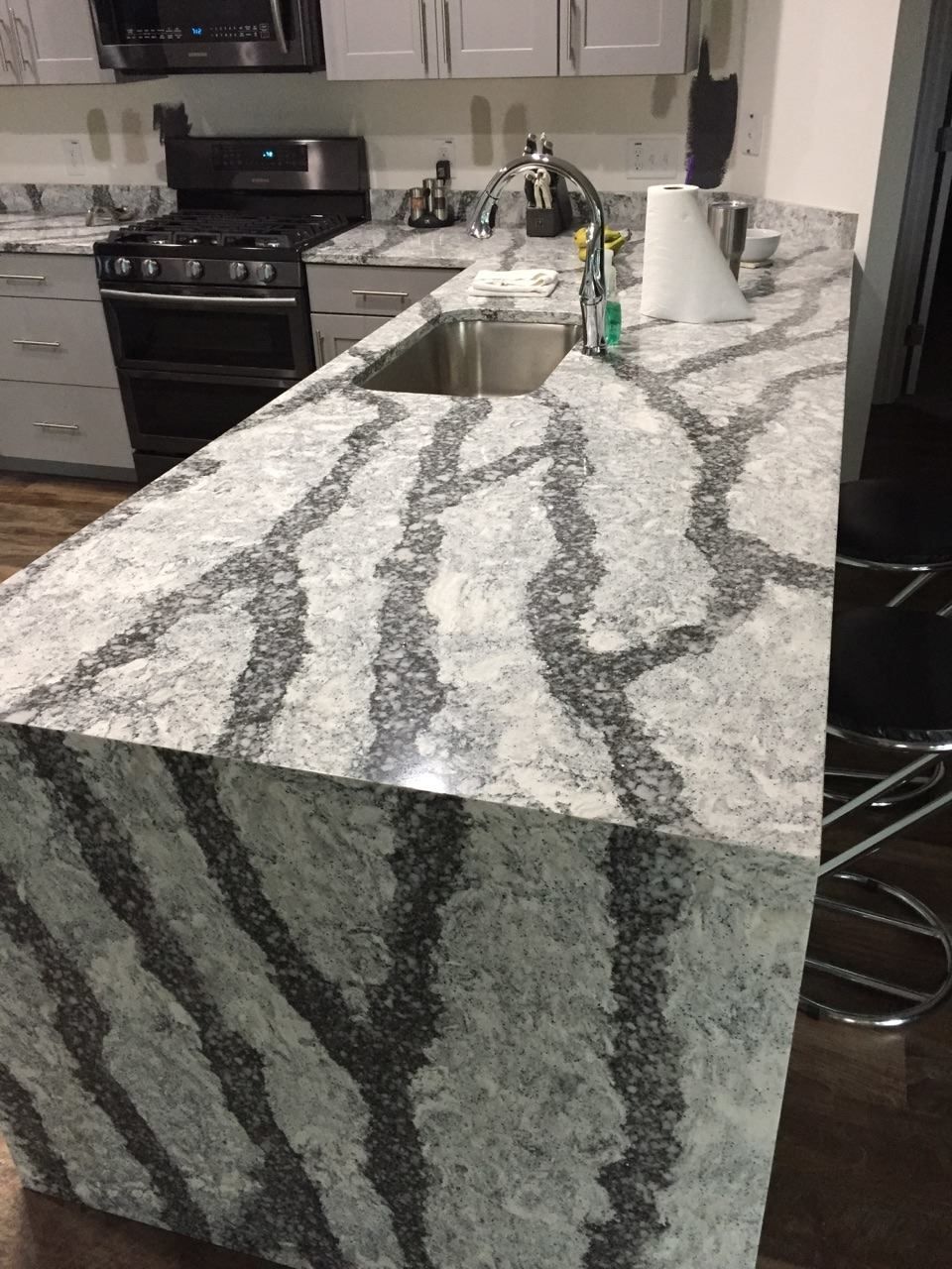 Kitchen with a granite countertop featuring dark, vein-like patterns against a light background, and a stainless steel sink.