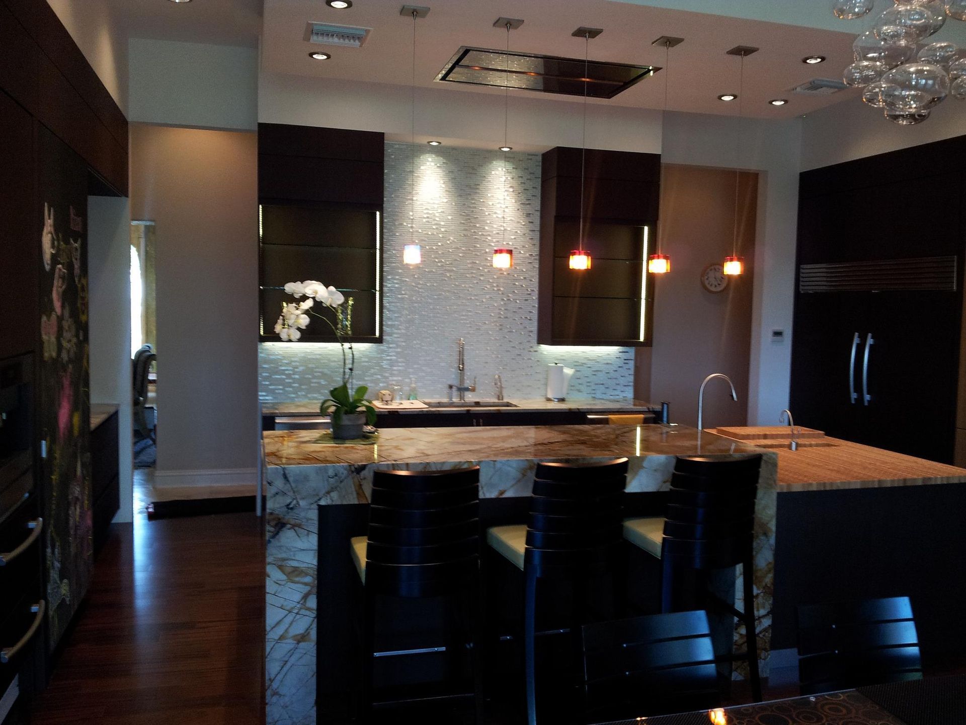 Modern kitchen with dark cabinetry, granite countertops, and breakfast bar seating.