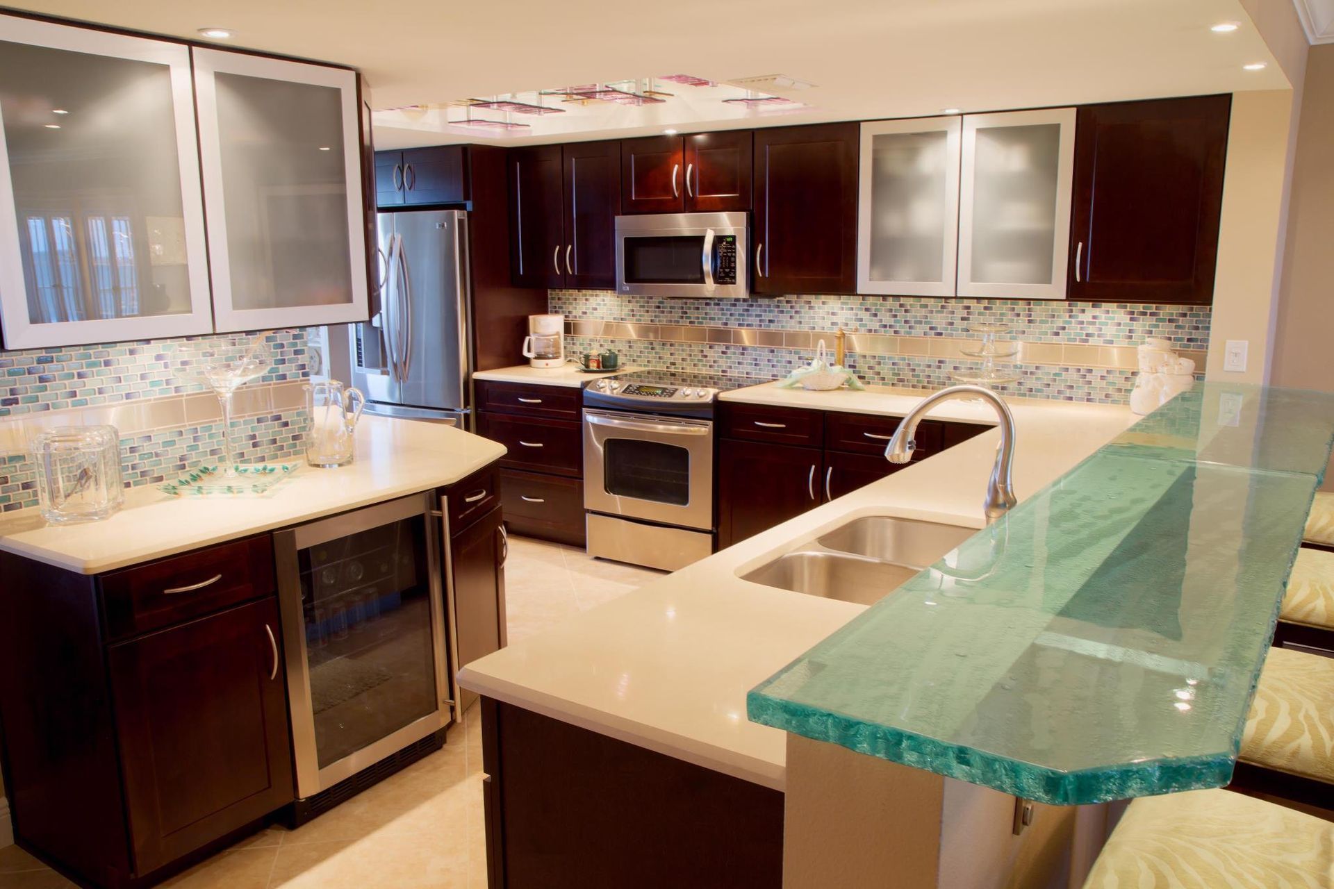 Modern kitchen with dark brown cabinets, stainless steel appliances, and a glass countertop.