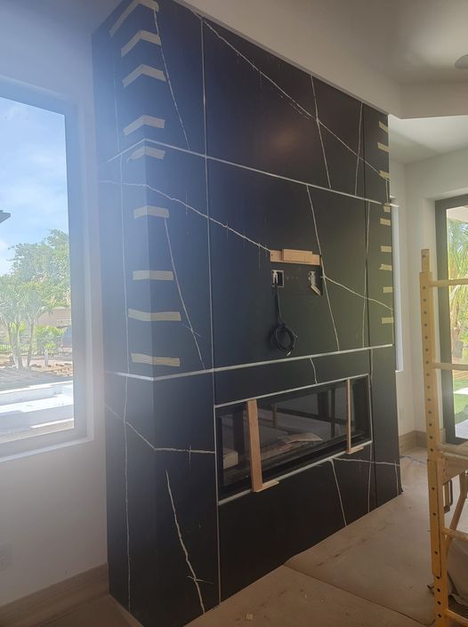 Black tiled fireplace with white veining, under construction, wood framing visible.