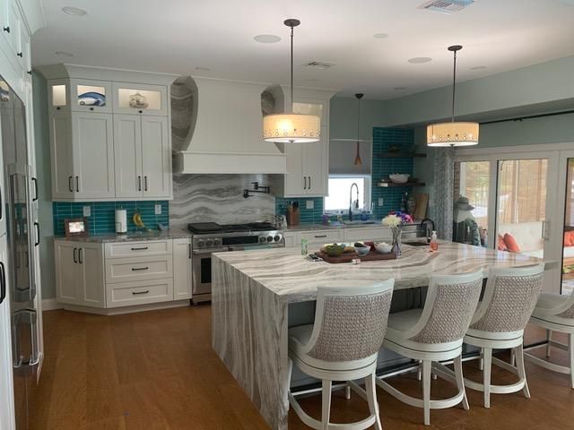 Elegant white kitchen with turquoise accents, marble countertops, and island seating.