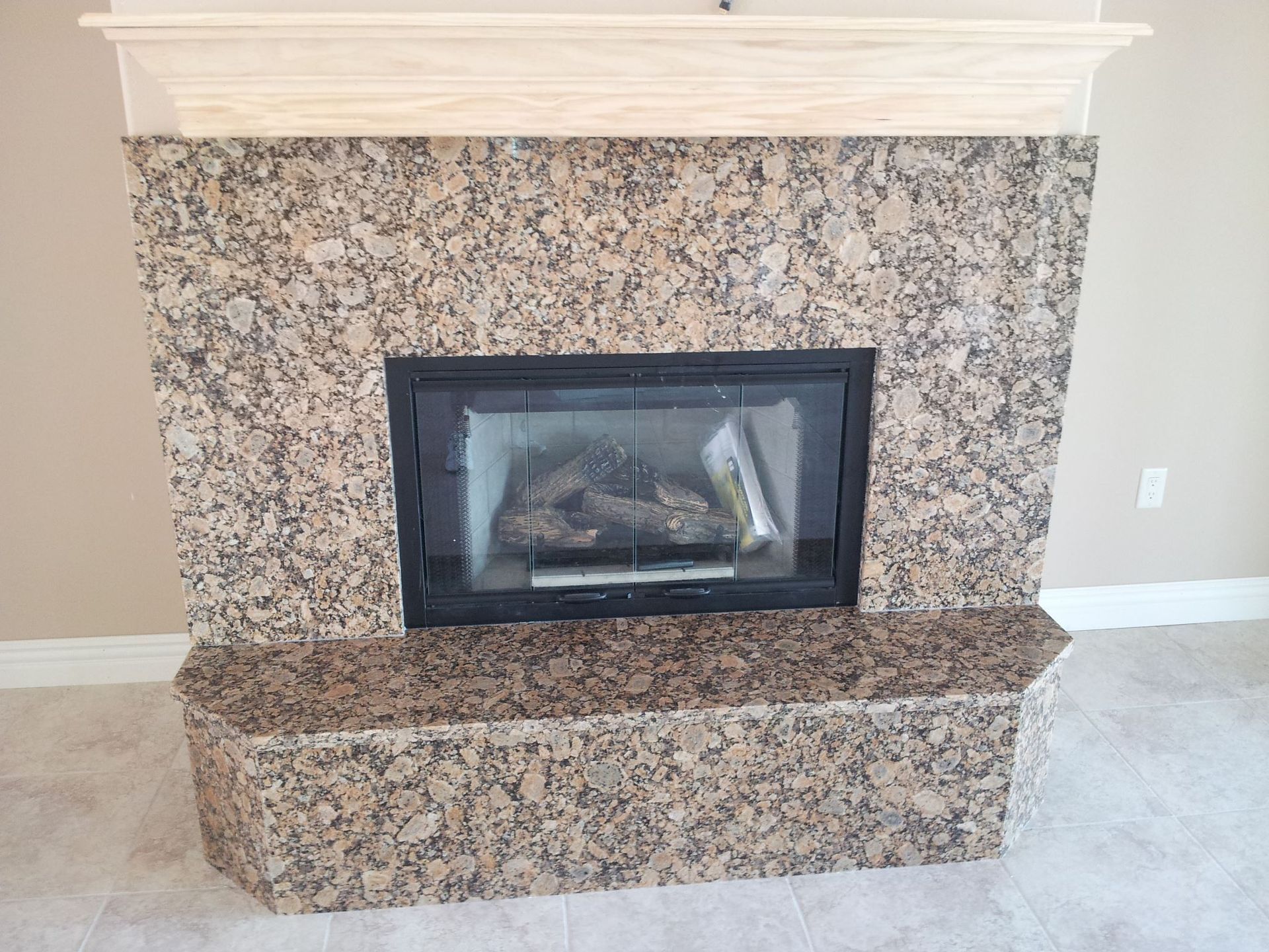 Fireplace with granite surround, wooden mantel, and glass-door firebox.