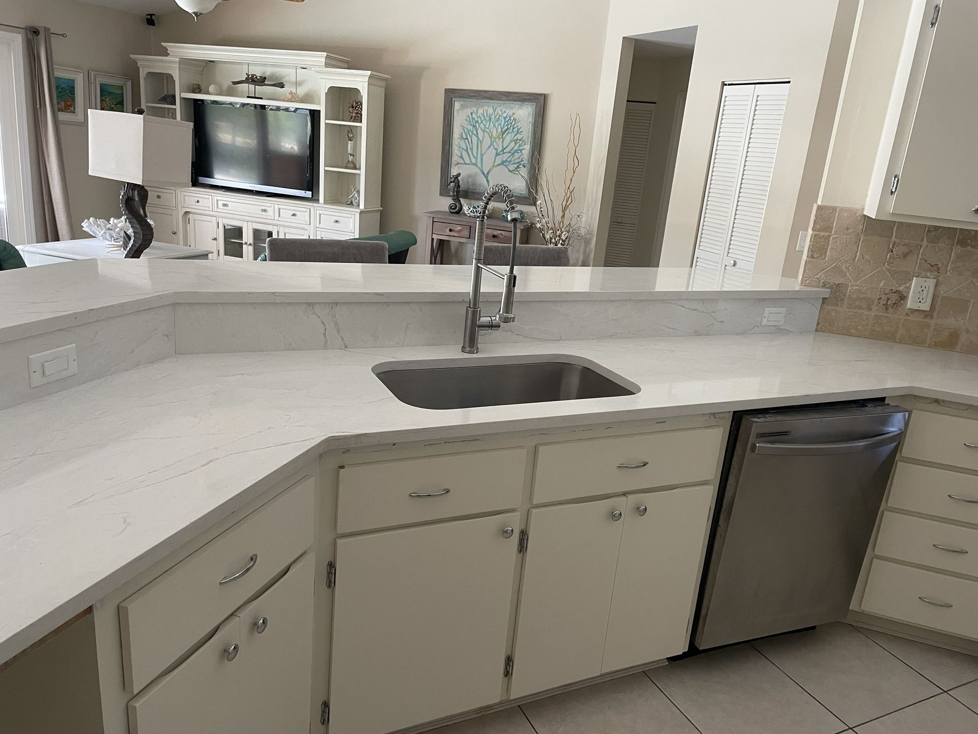 Kitchen with white cabinets, light countertops, and a stainless steel sink and dishwasher.