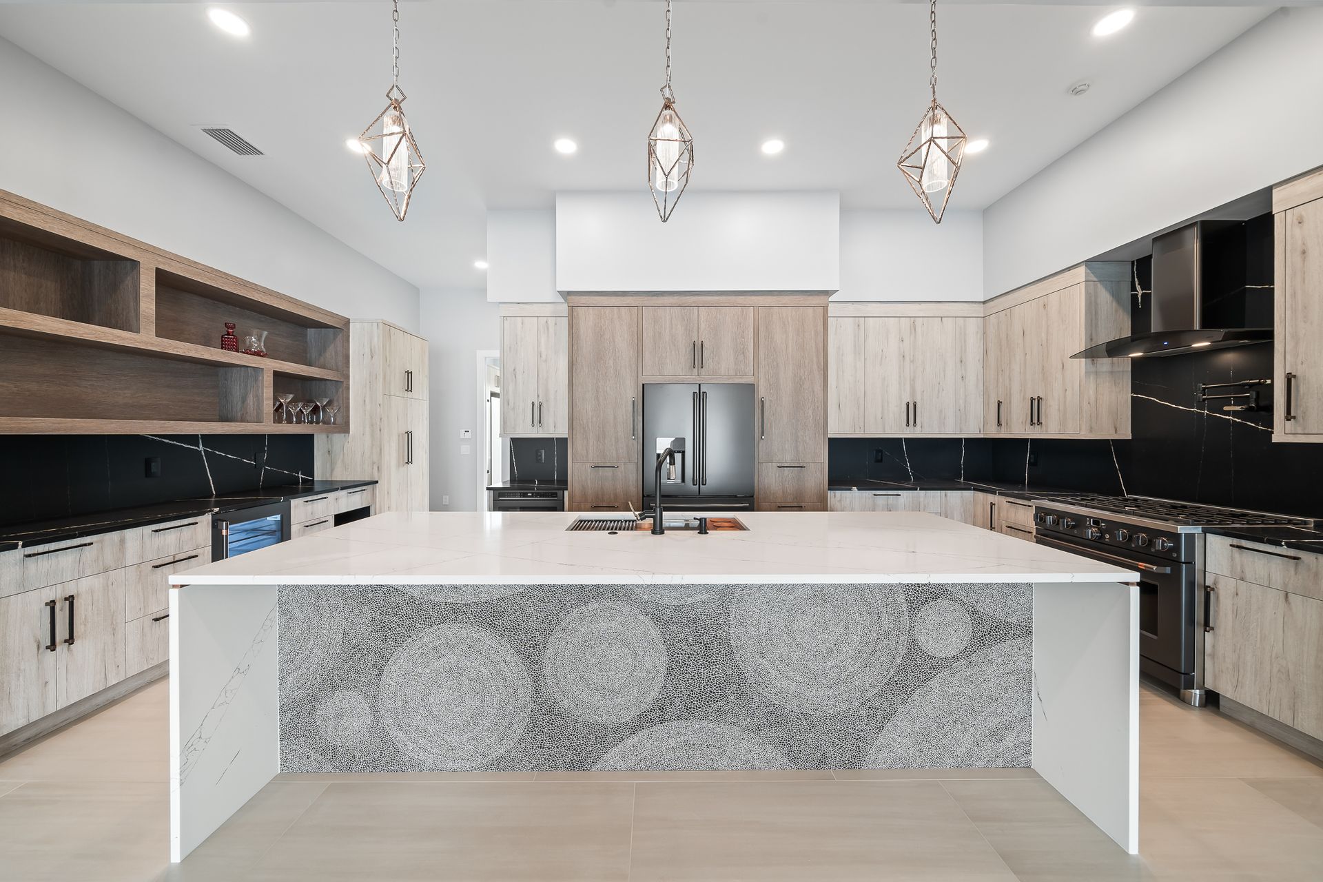 Modern kitchen with large island, light cabinets, and decorative pendant lights.