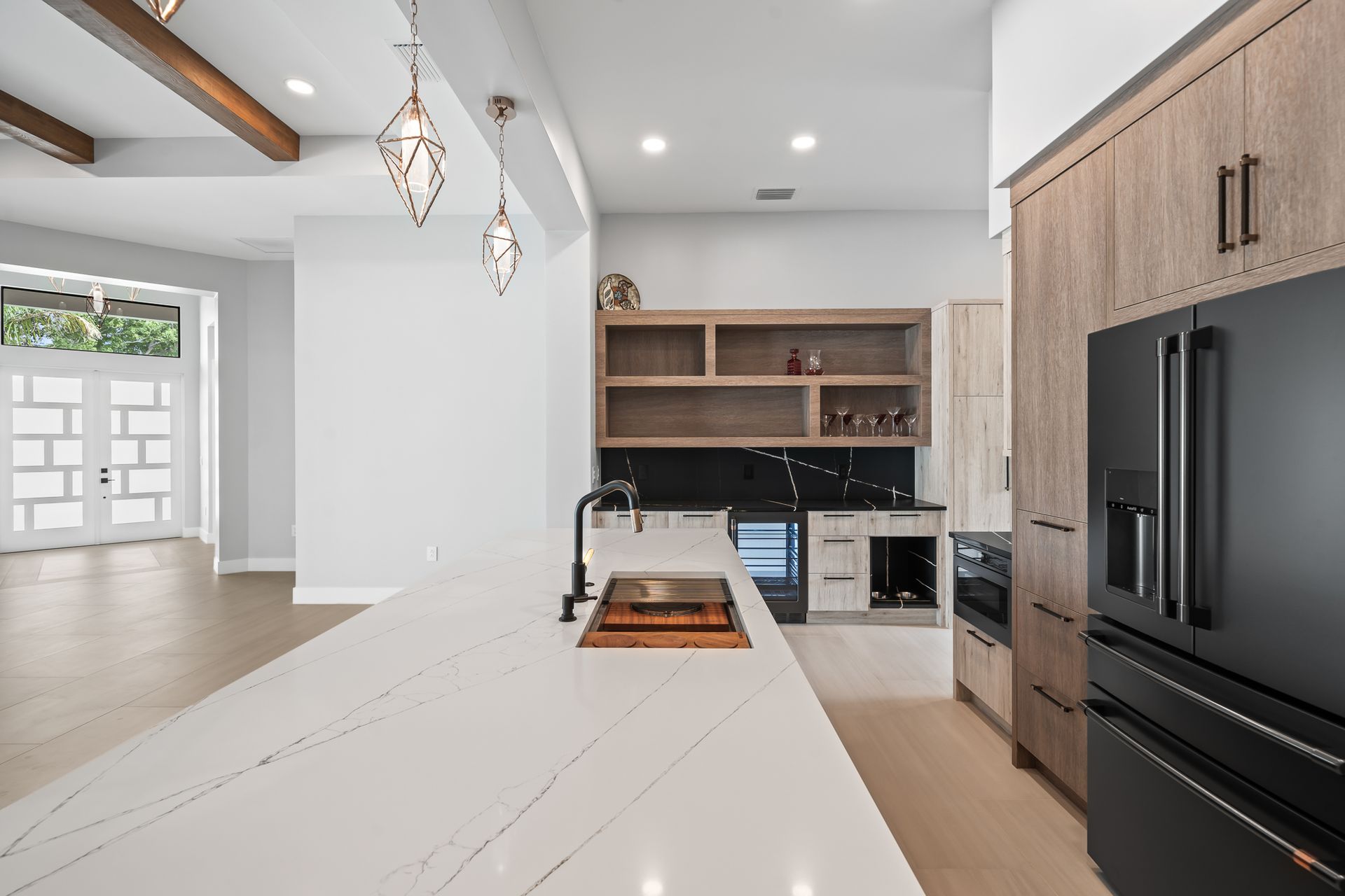Modern kitchen with white countertop, black appliances, and wooden cabinets and shelving.