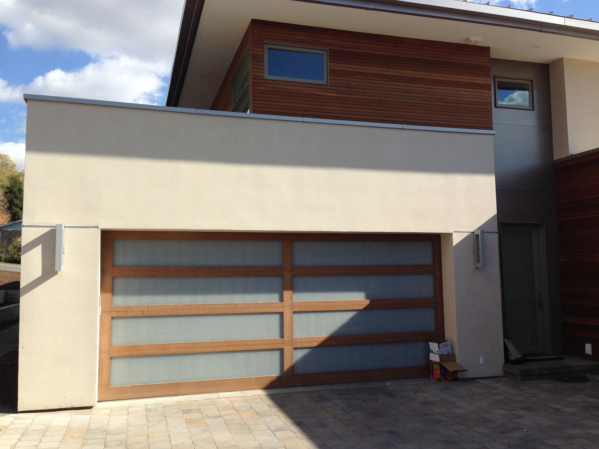 Modern house exterior with a wide garage door and beige, wood, and gray facade