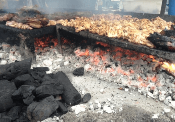 Charcoal and meat grilling over hot coals on a large open barbecue grill