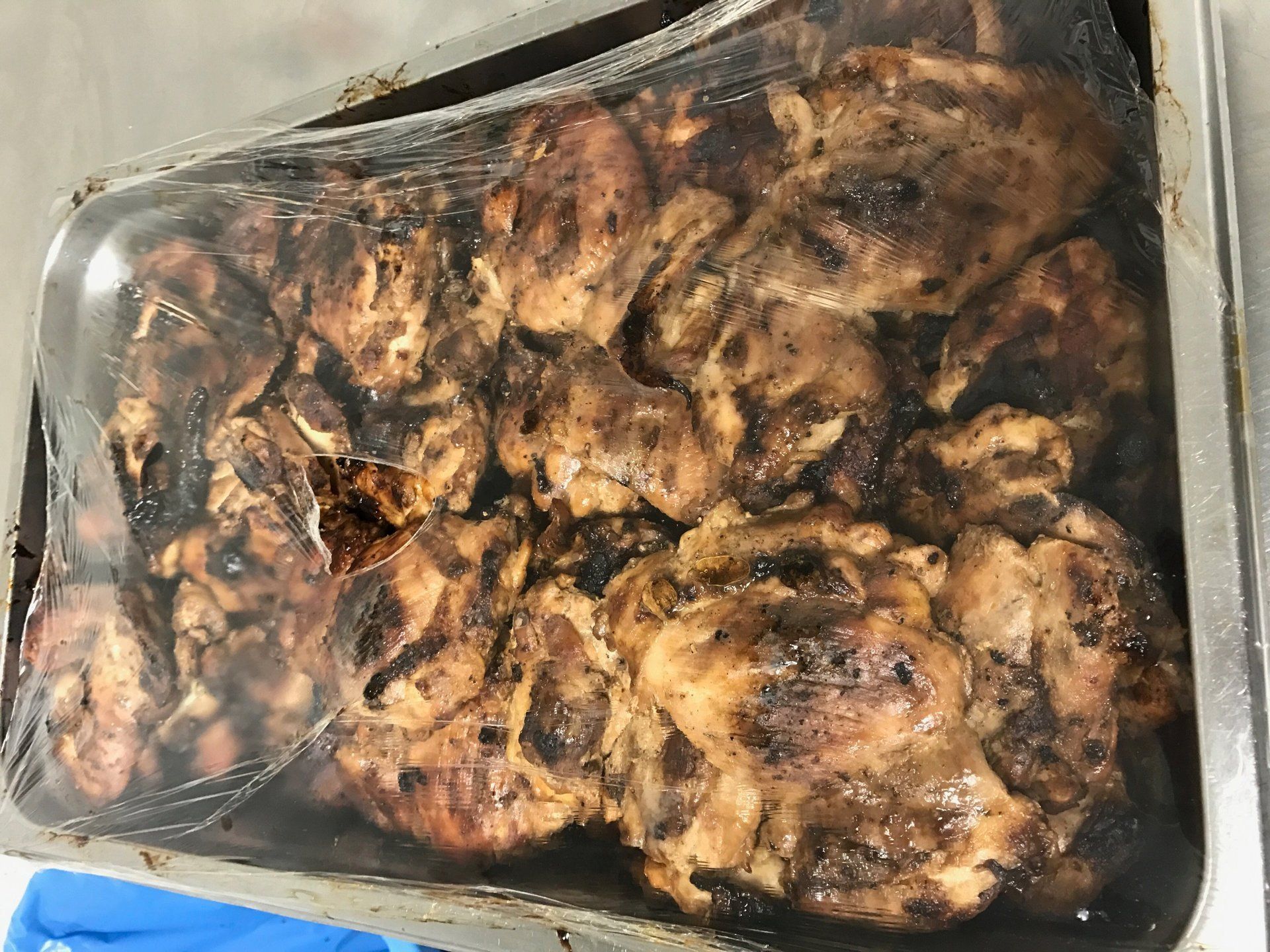 Tray of charred, roasted chicken pieces in a glass baking dish