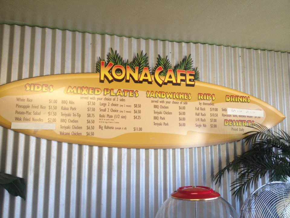 Kona Cafe Hawaiian Barbecue And Catering menu board on striped wall, shaped like a surfboard with yellow and orange text.