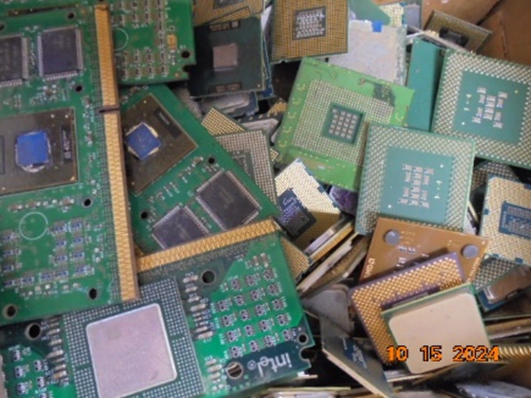 A pile of various computer processors and green circuit boards stacked together in a bin.