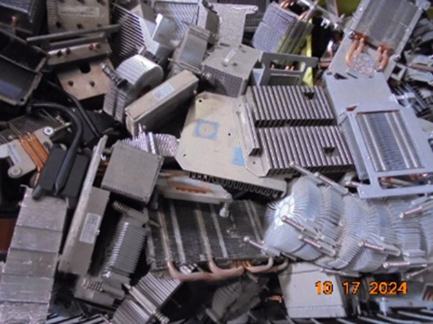 Pile of assorted metallic computer heat sinks and components, mostly gray, some with fins.