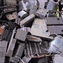 Pile of assorted metallic computer heat sinks and components, mostly gray, some with fins.