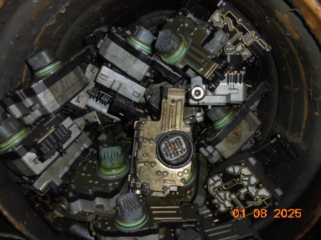 A metal container filled with used automotive transmission control modules