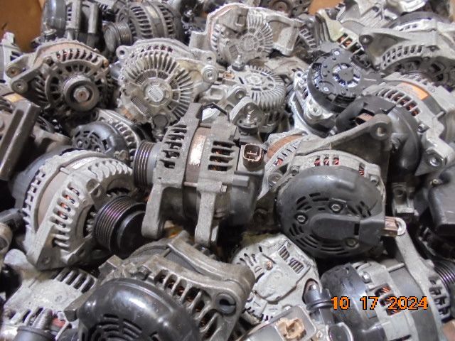 Pile of used car alternators, mostly silver