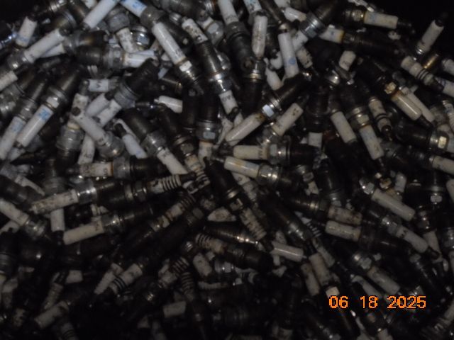 Pile of used spark plugs in a dark container