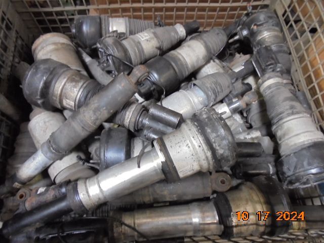 Heap of used automotive shock absorbers in a bin