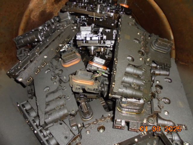 Dark, metal mechanical parts piled inside a cylindrical container