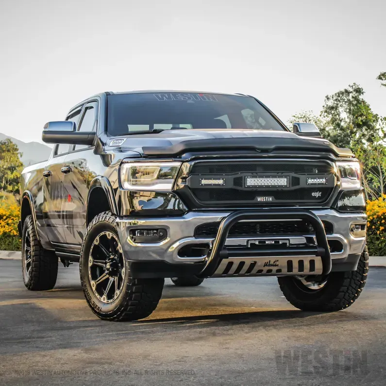 Black lifted pickup truck parked on grass with trees in the background