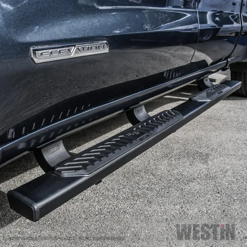 Black side step rail with textured step on a beige SUV parked on pavement