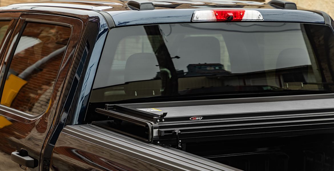 Red pickup truck with a black tonneau cover parked in the snow