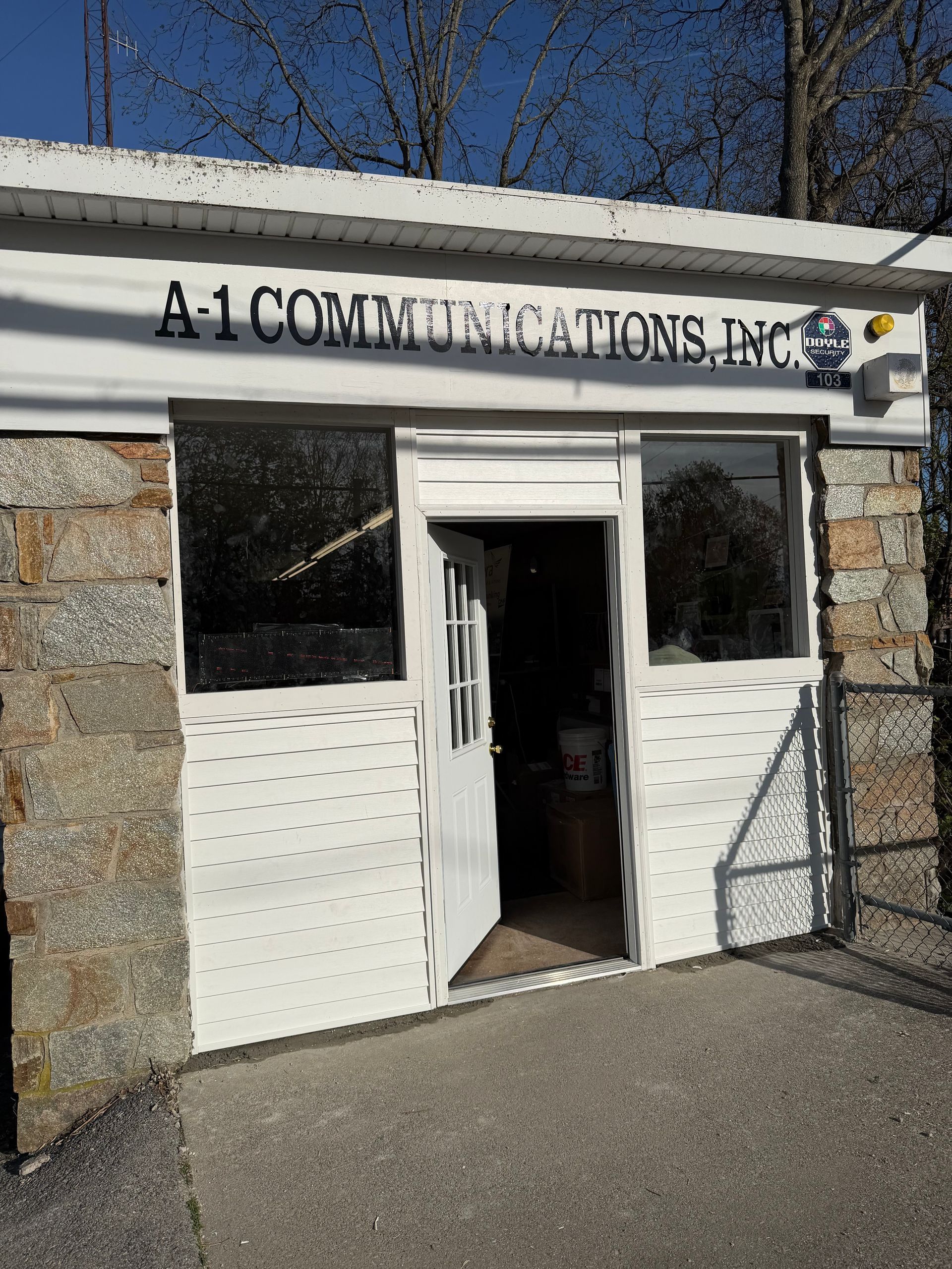 Storefront entrance for A-1 Communications, Inc. with open white doors and stone walls