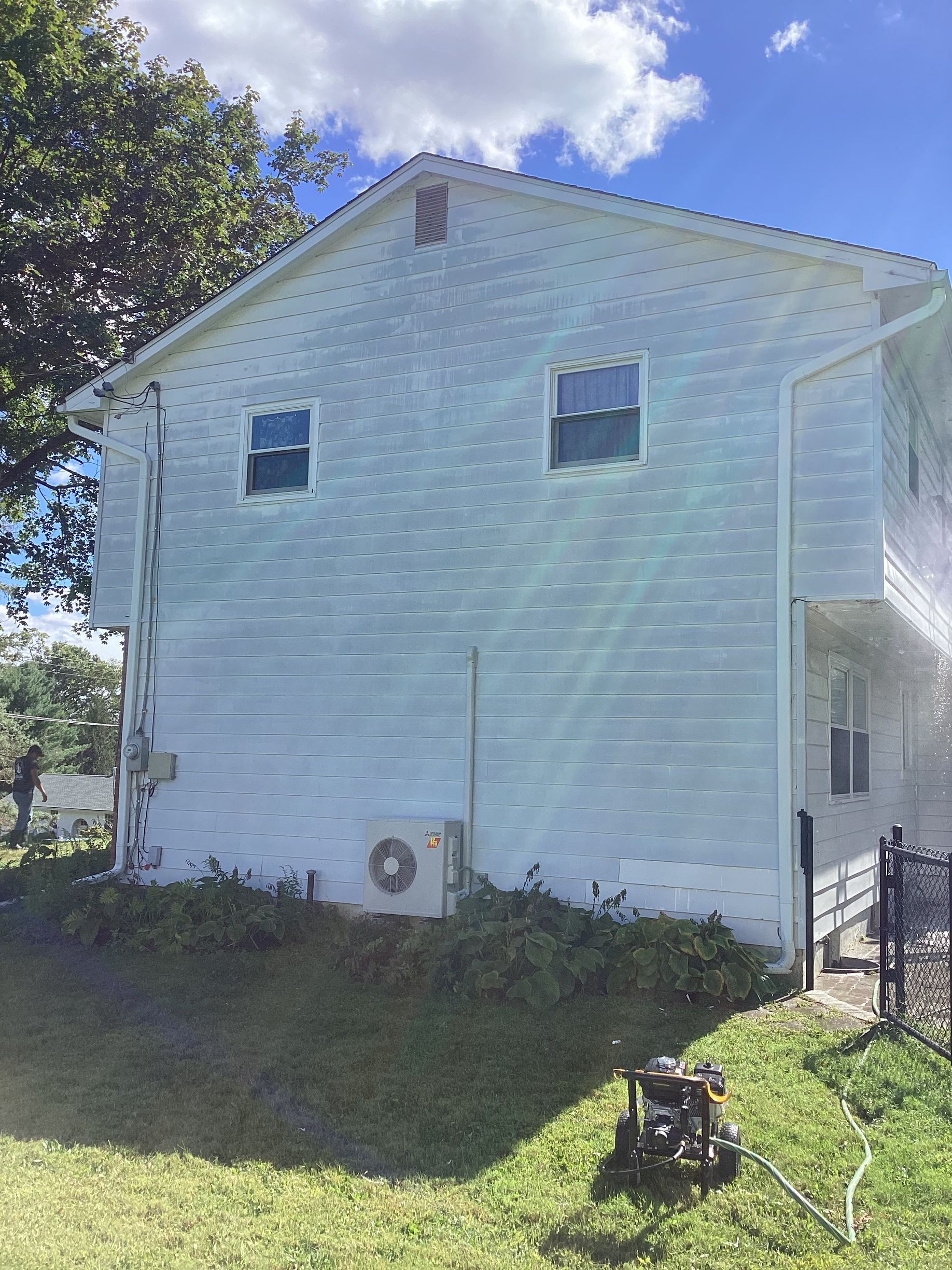 Side view of a light blue two-story house with two windows. A mini split air conditioner is on the wall.