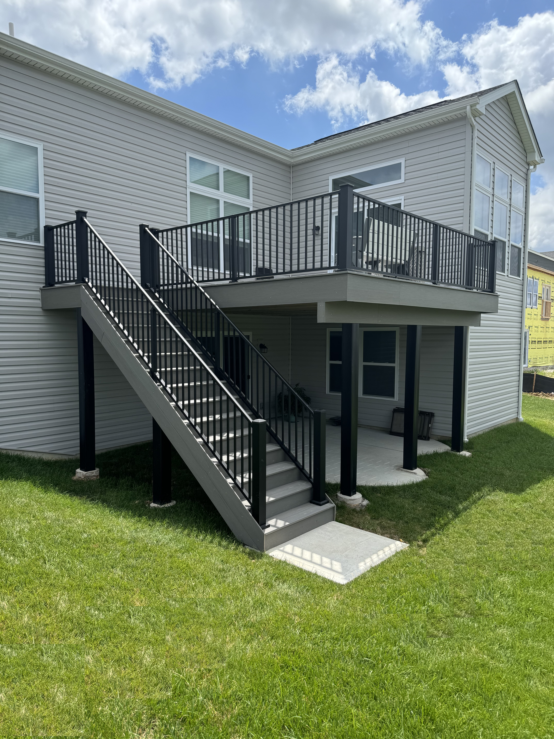 A large white house with a large deck and stairs leading up to it.