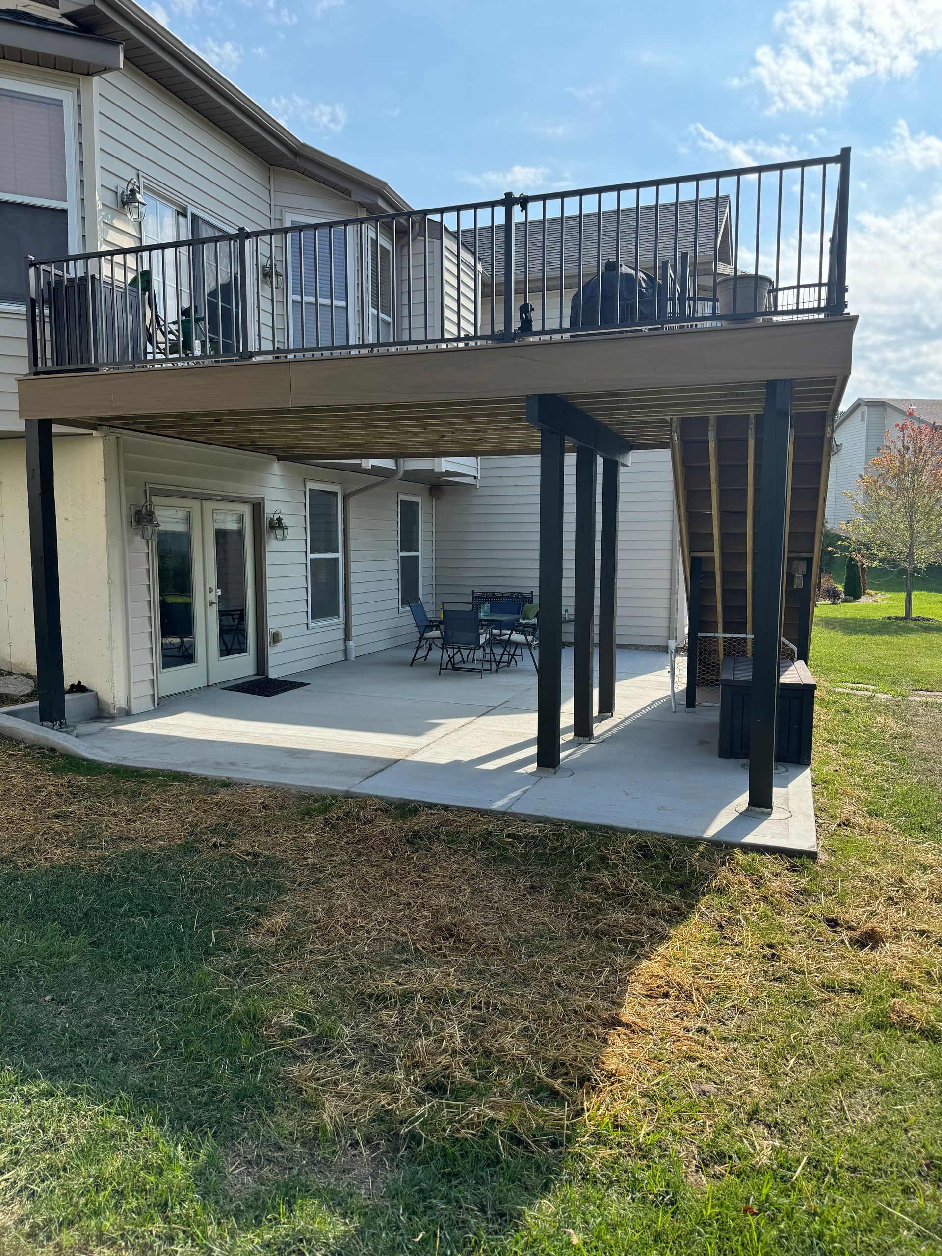 A large deck with a railing is sitting in the backyard of a house.