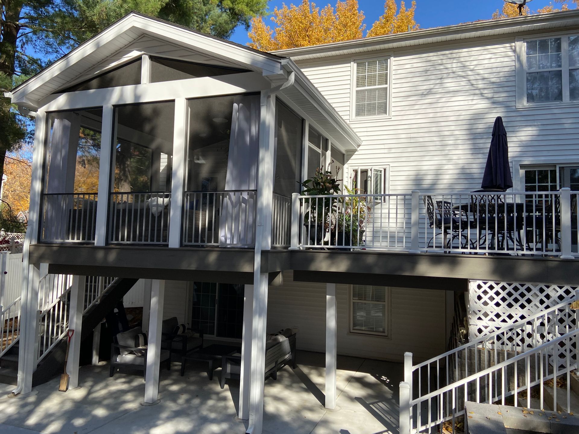 The back of a house with a screened-in porch and stairs.