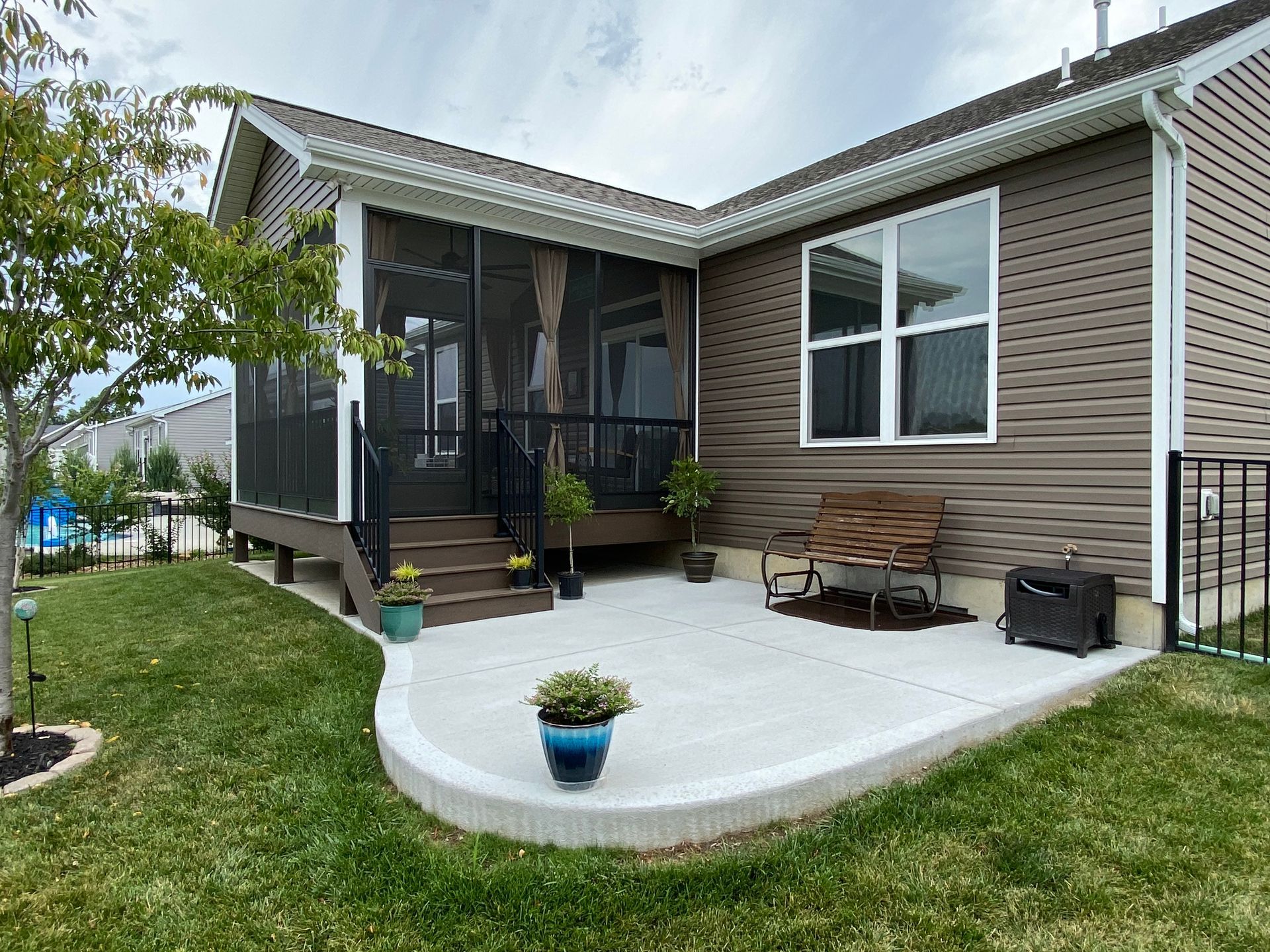 A mobile home with a screened in porch and patio.