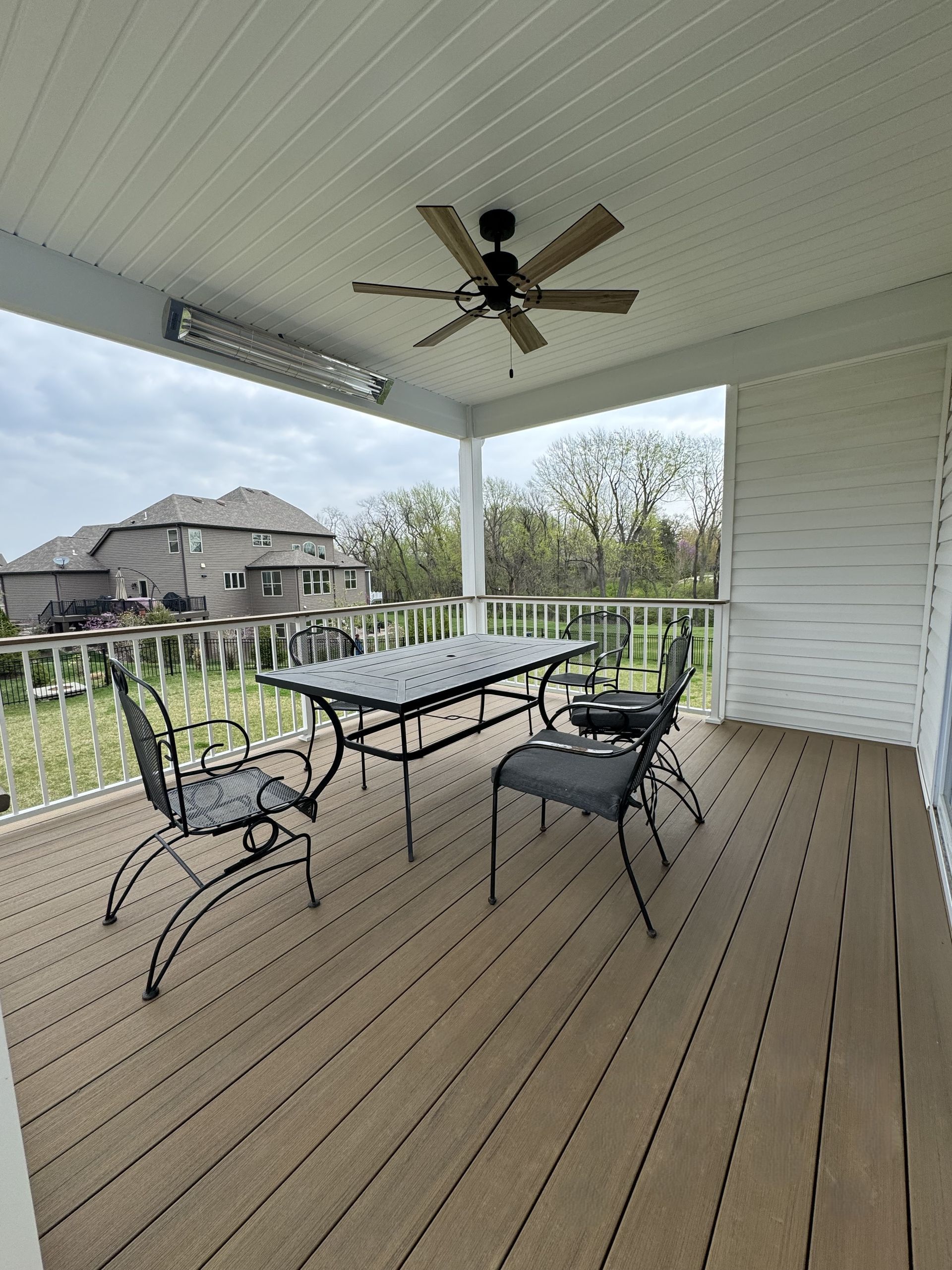 A porch with a table and chairs and a ceiling fan.