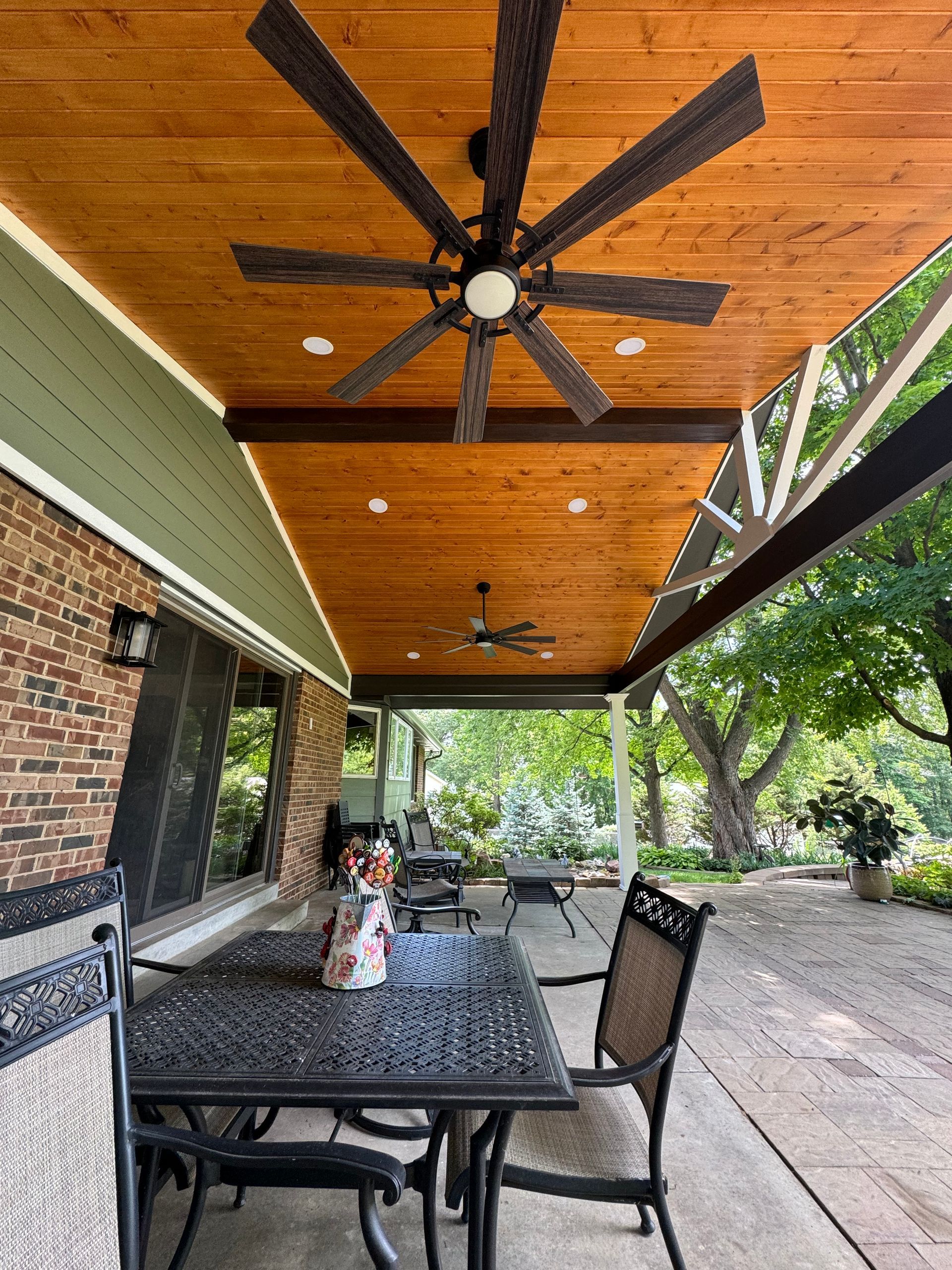 A patio with a table and chairs and a ceiling fan.