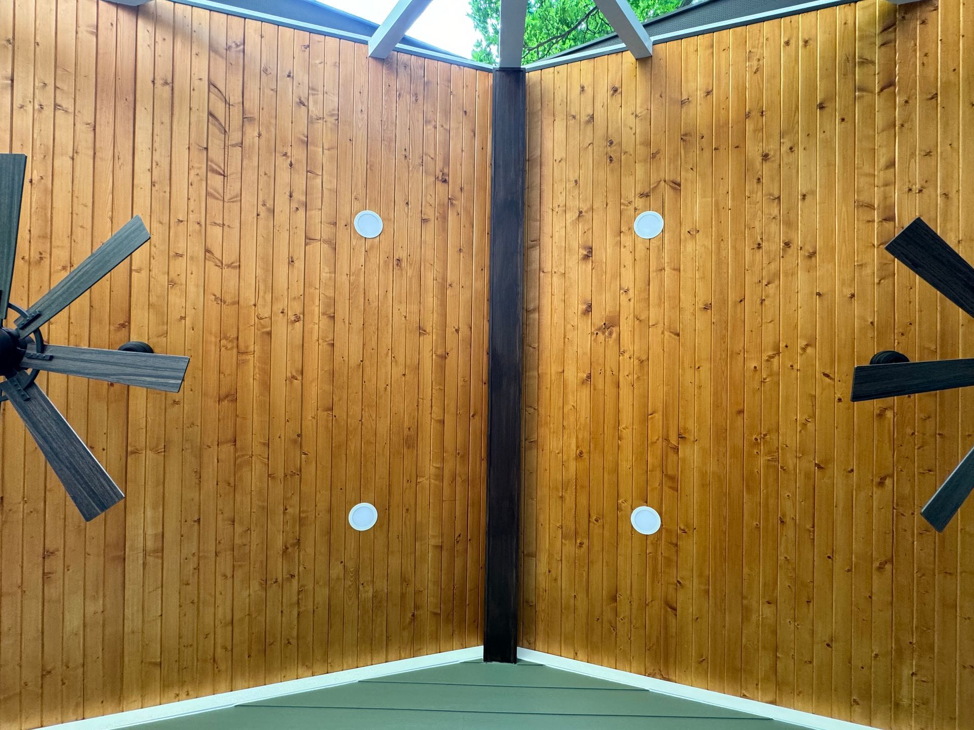 A ceiling fan is hanging from the ceiling of a wooden room.