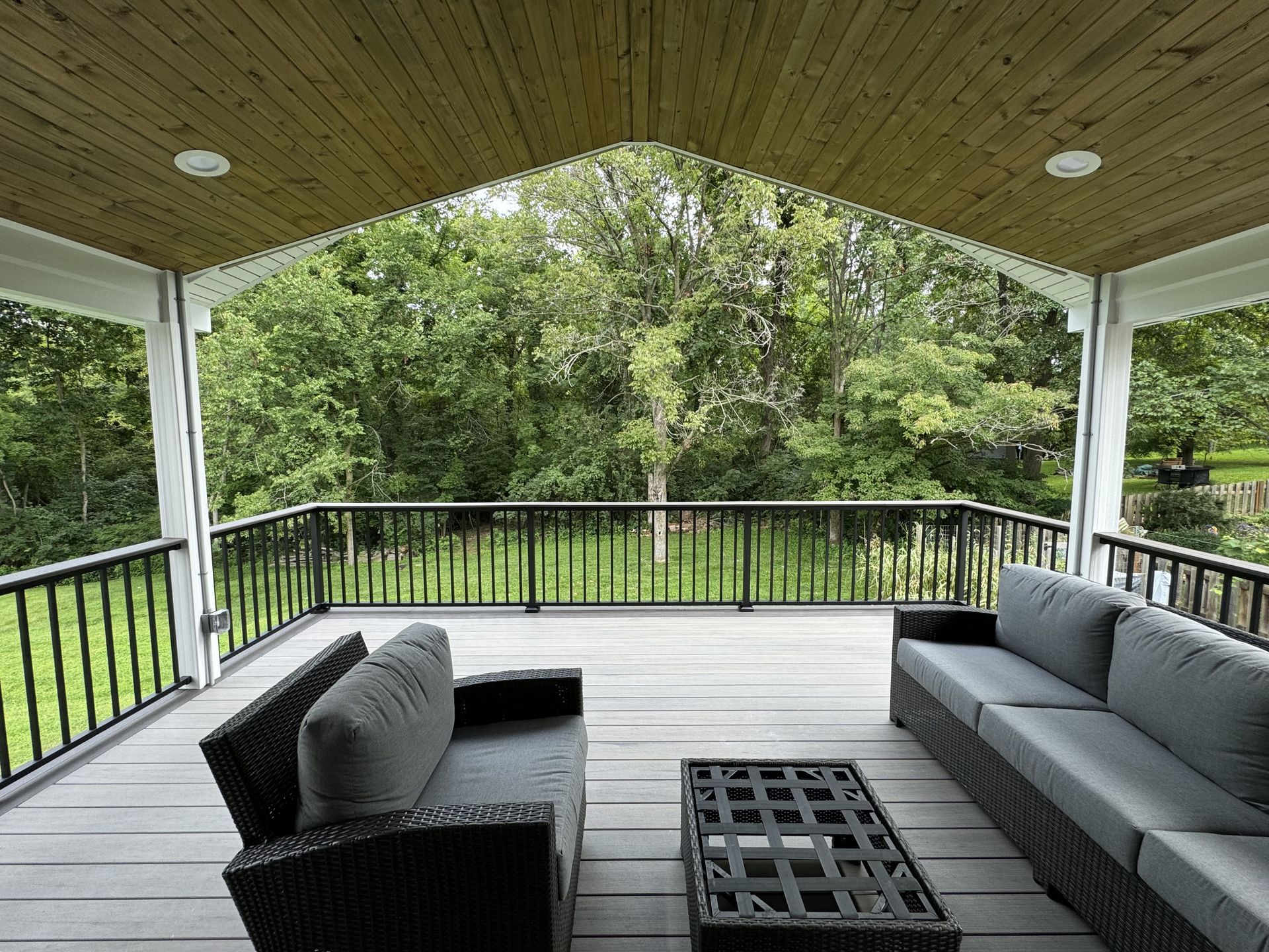 A porch with a couch and a table and trees in the background