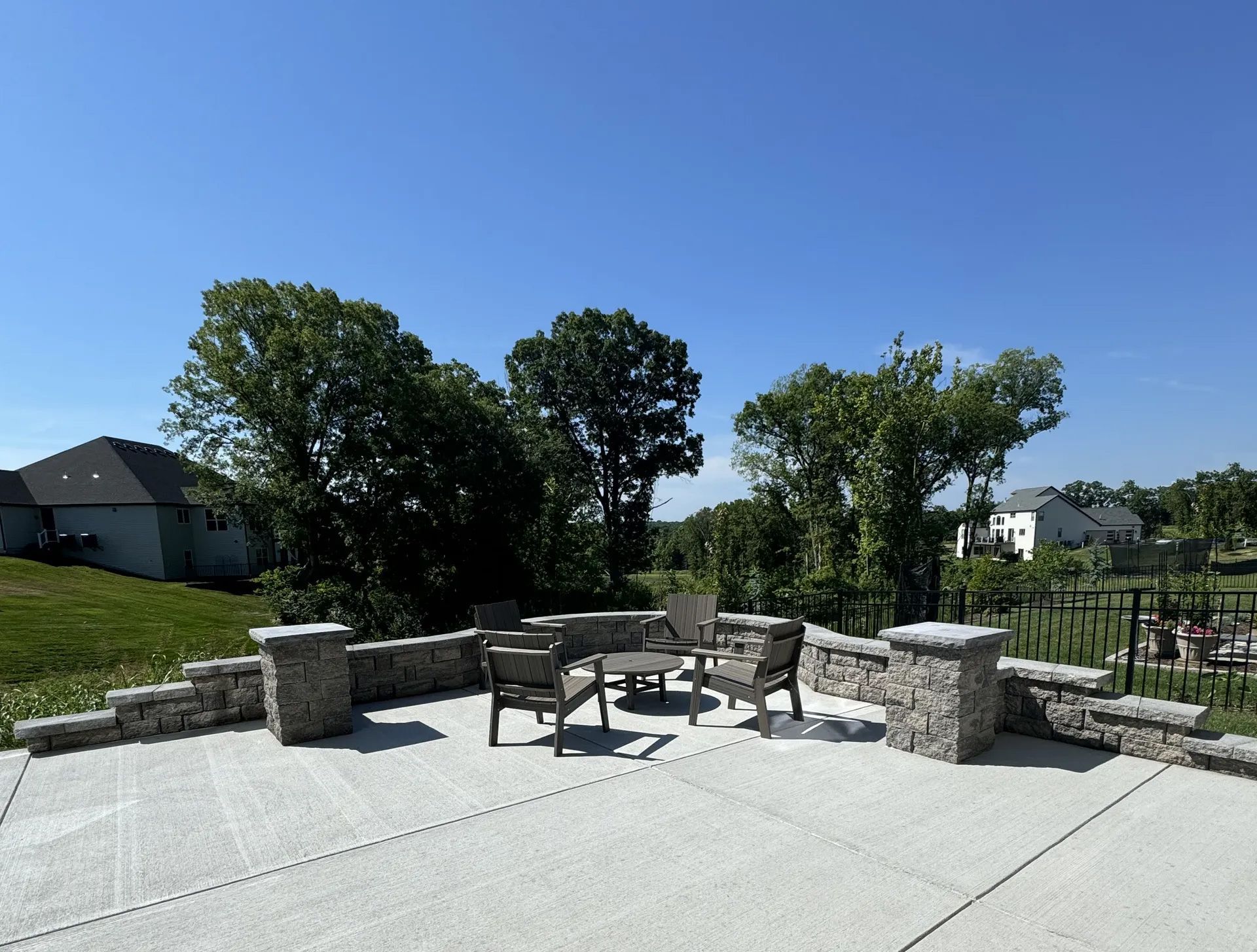 A patio with a table and chairs and trees in the background