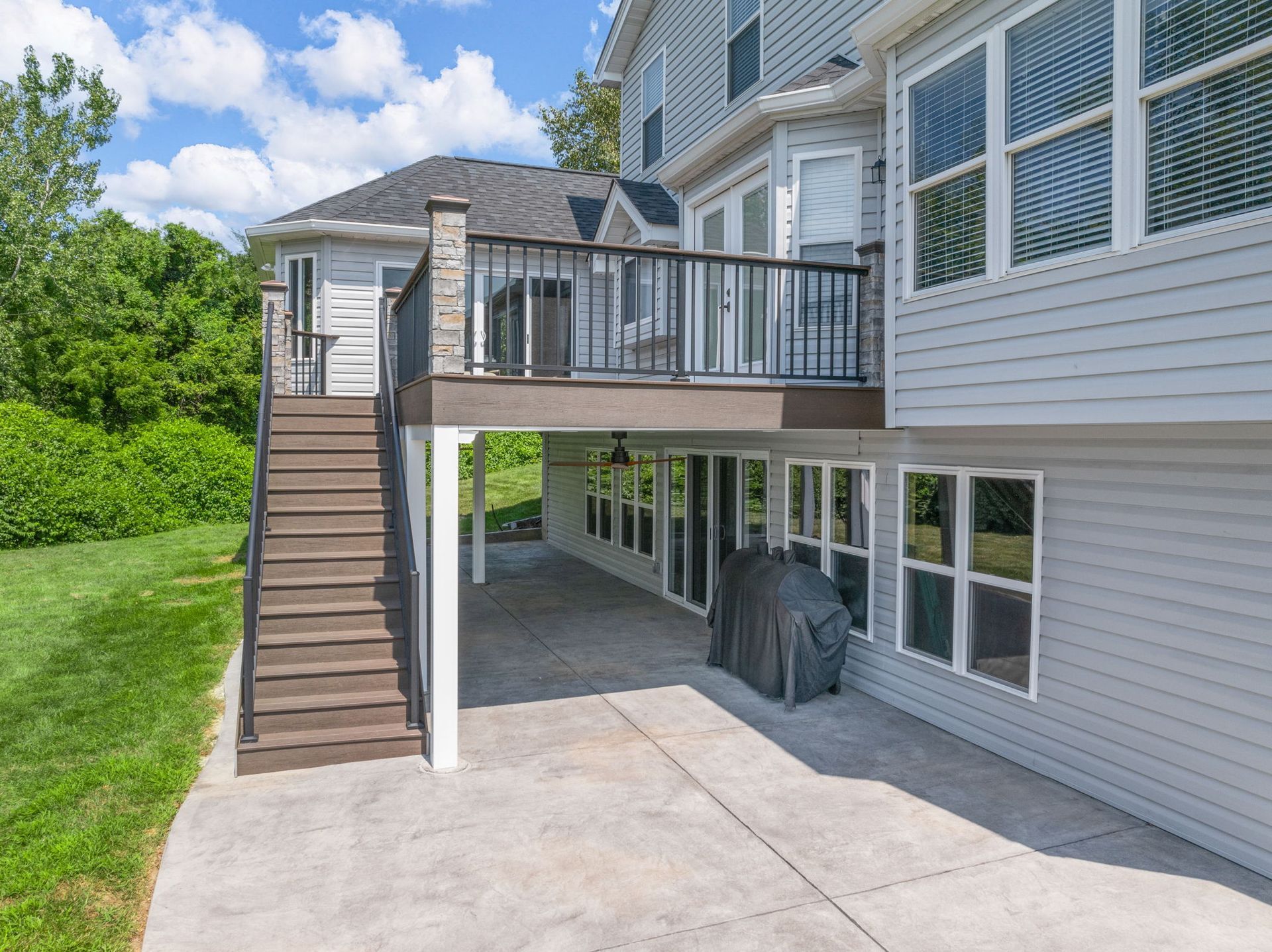 The back of a house with a large deck and stairs leading up to it.
