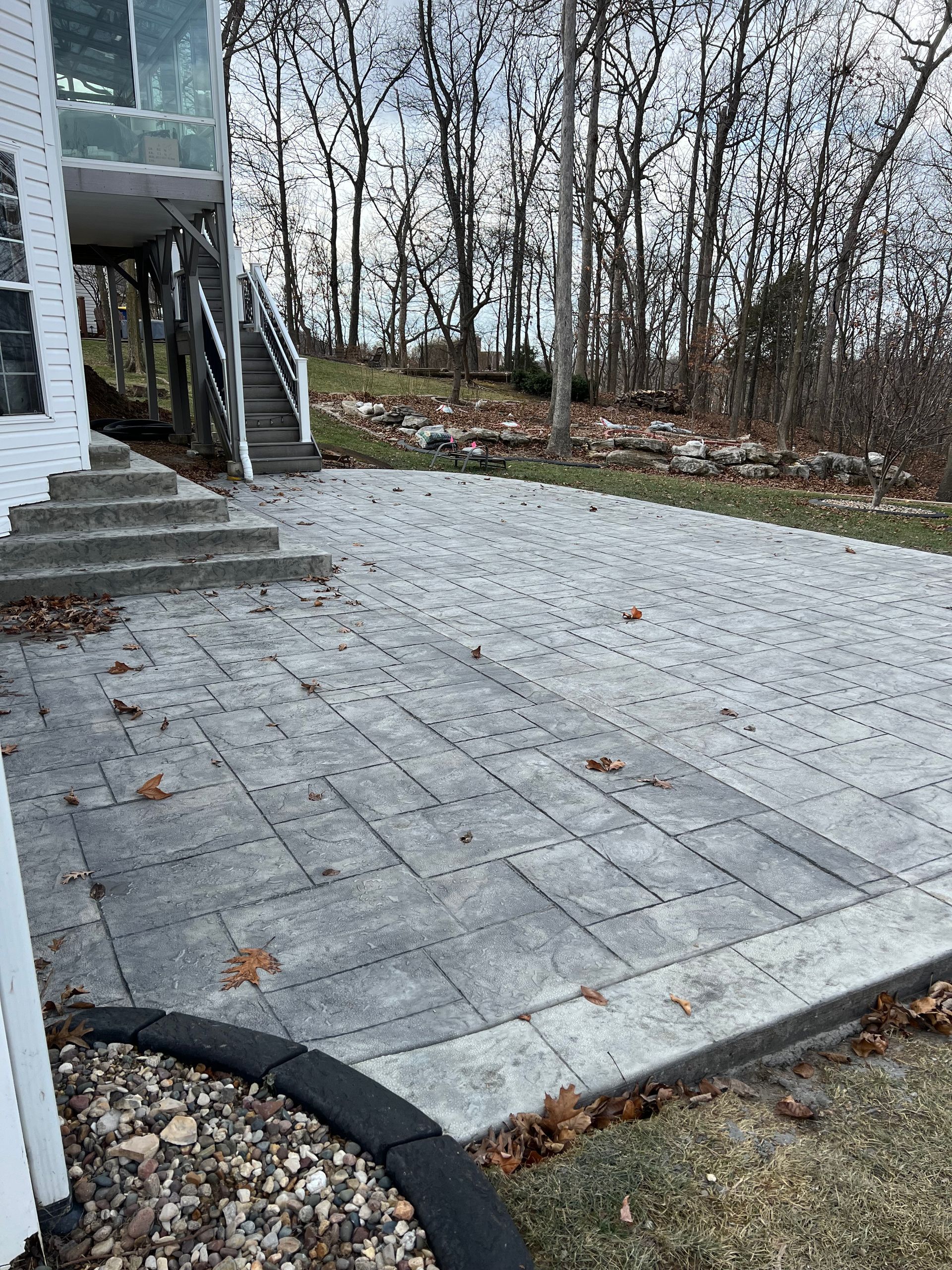 A patio with a house in the background and trees in the background.