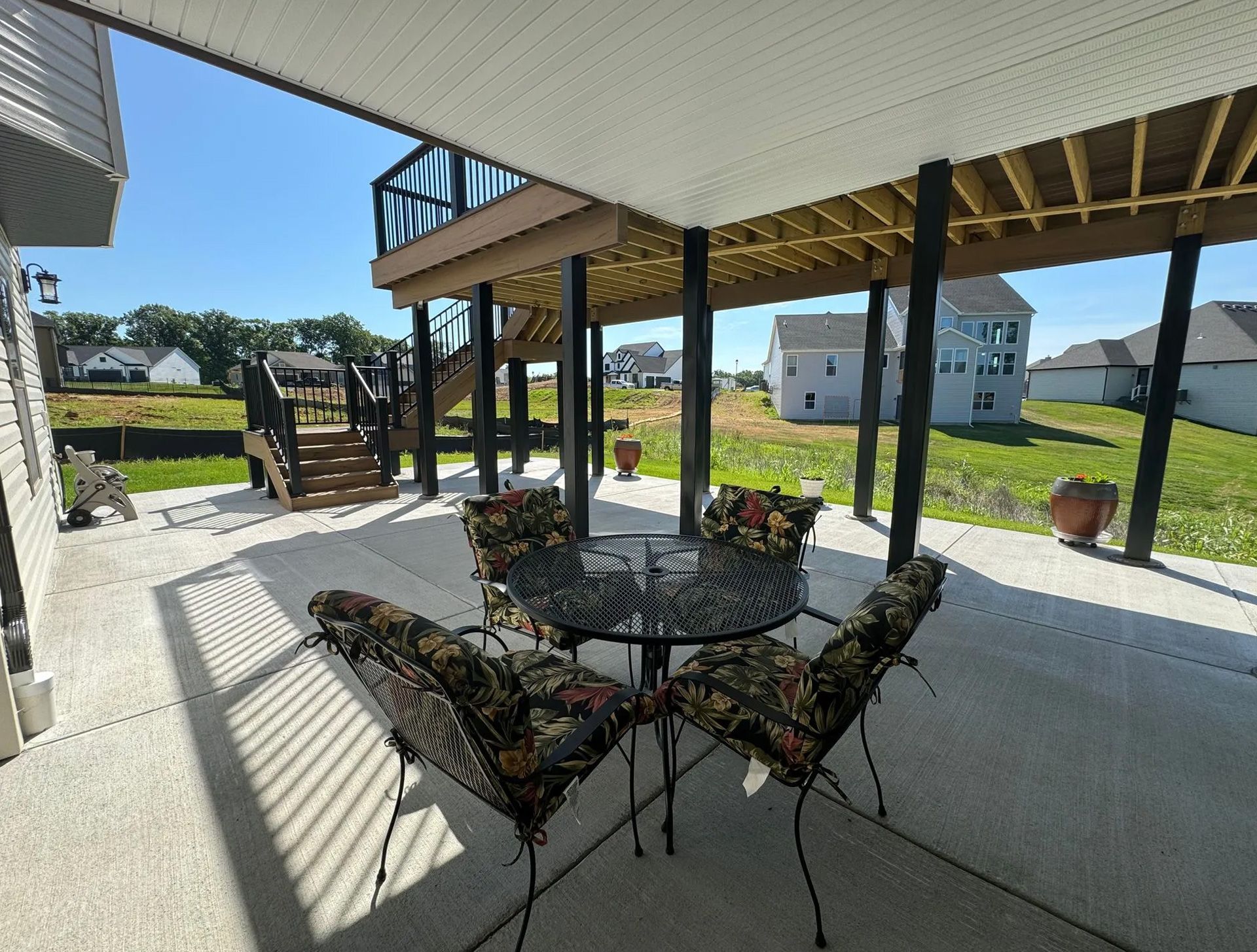 A patio with a table and chairs under a deck