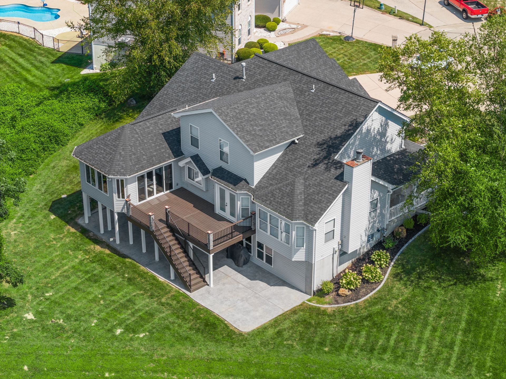 An aerial view of a large white house with a large deck.