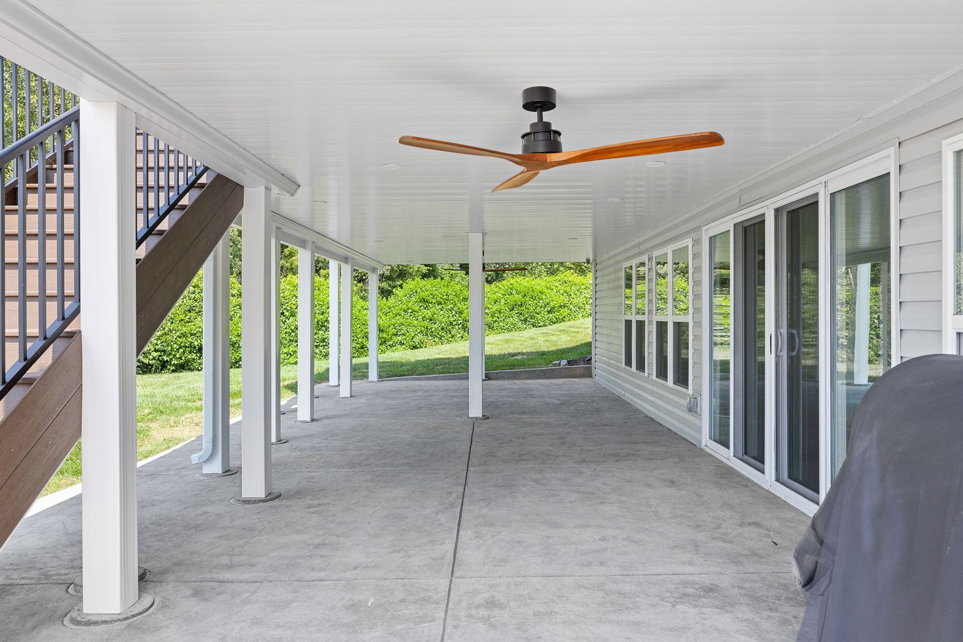 There is a ceiling fan on the porch of a house.