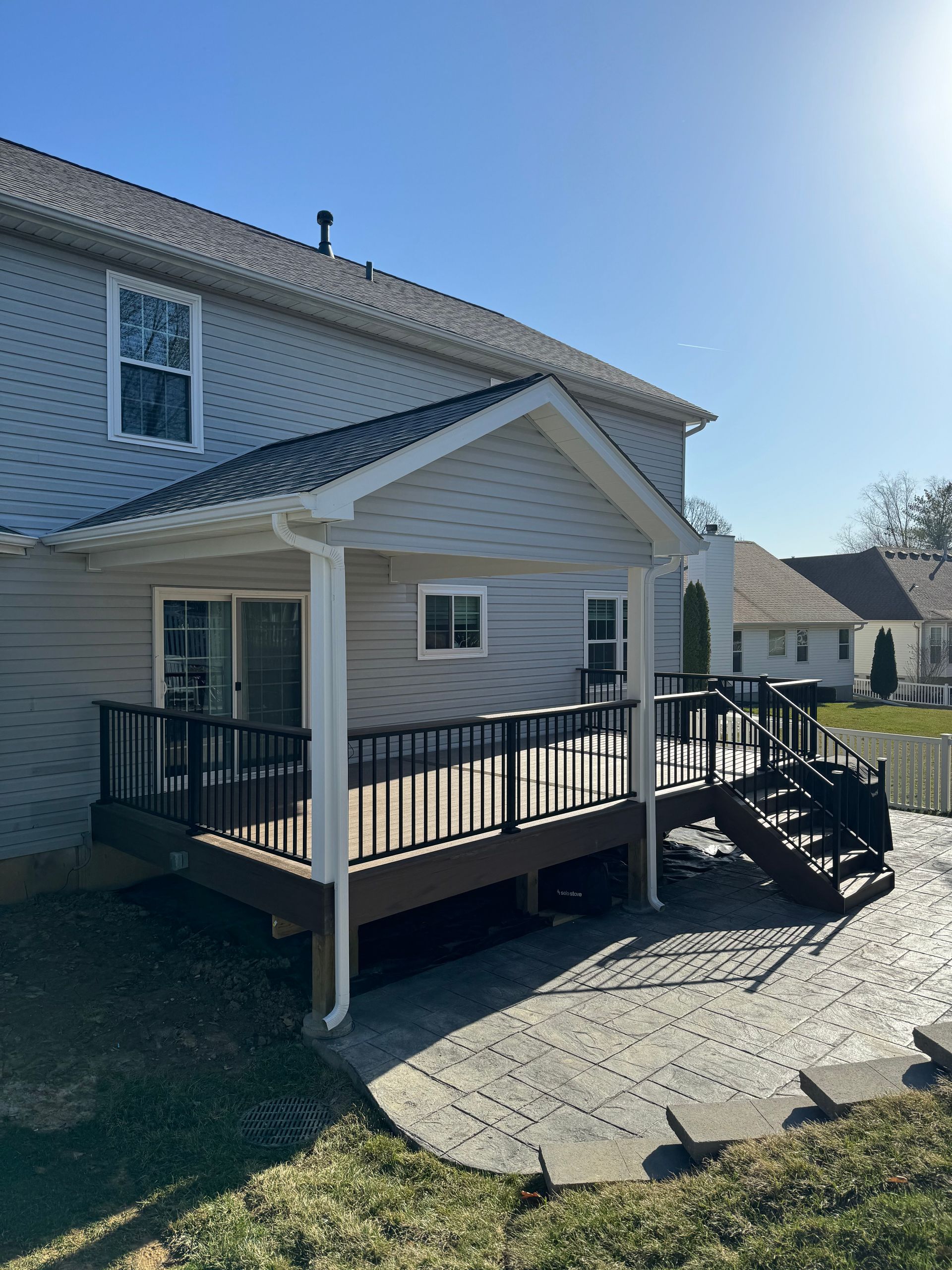 A house with a covered deck and patio in front of it.