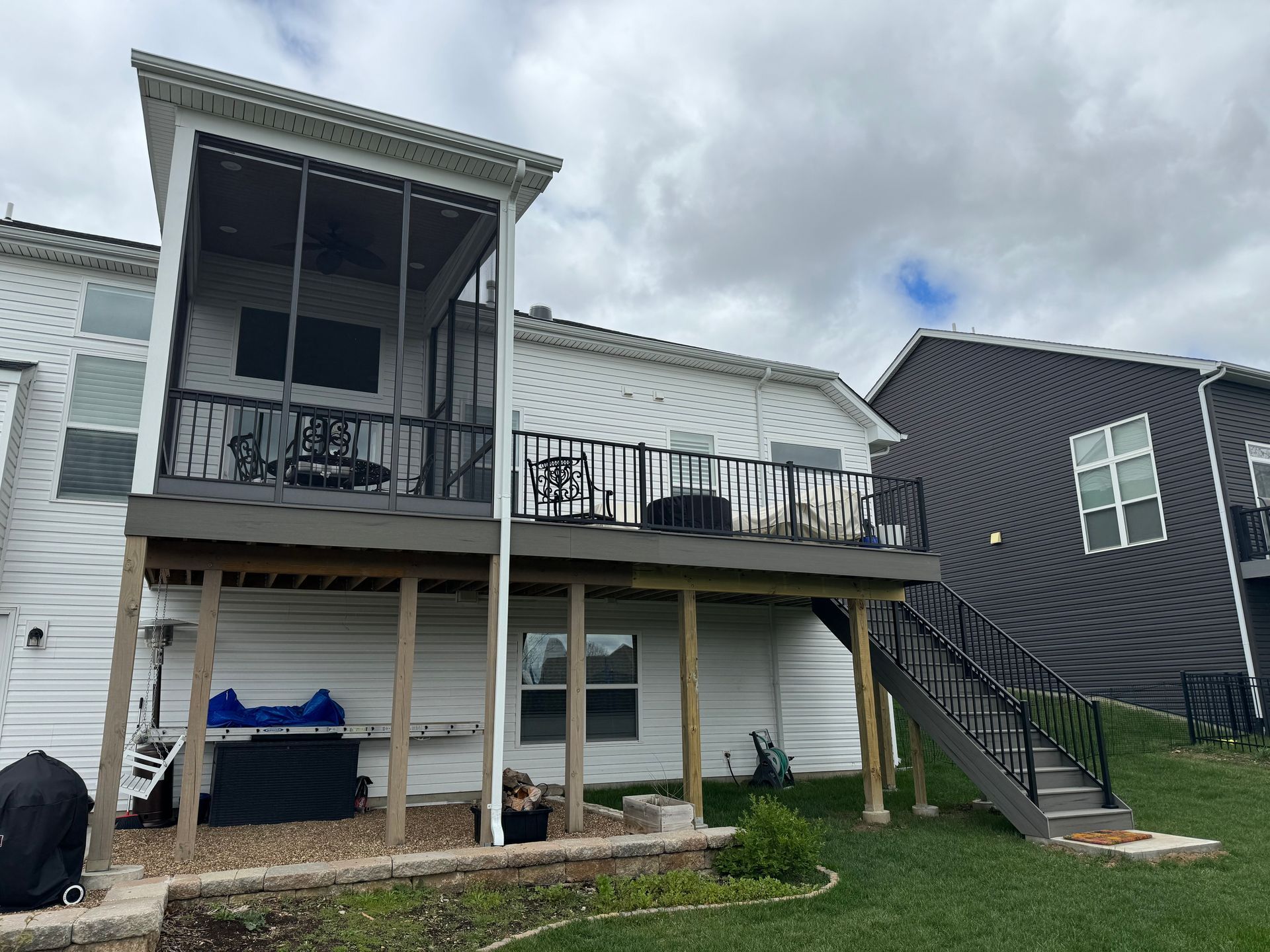 The back of a house with a screened in porch and stairs.
