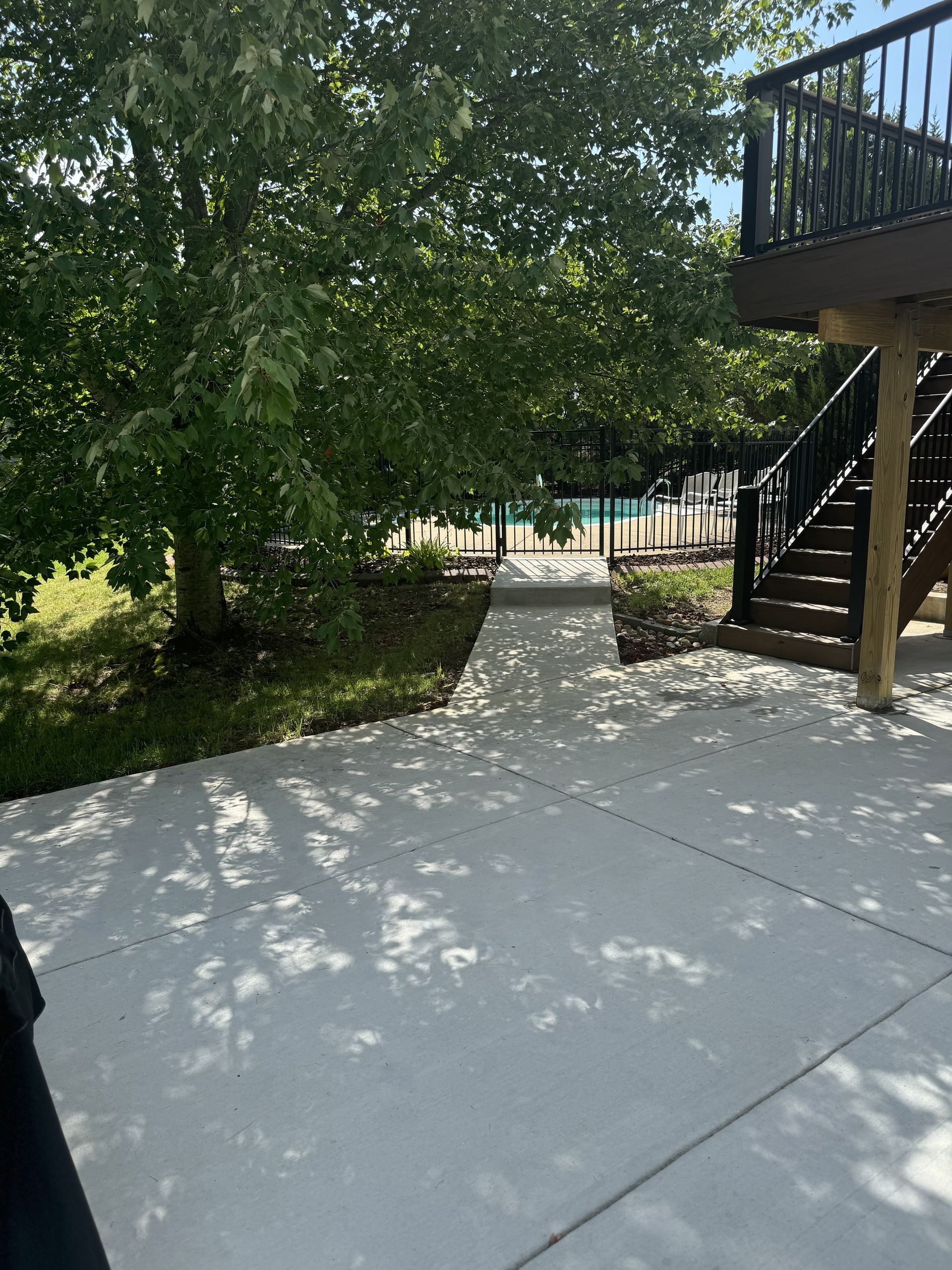 A patio with a deck and stairs leading to a pool.