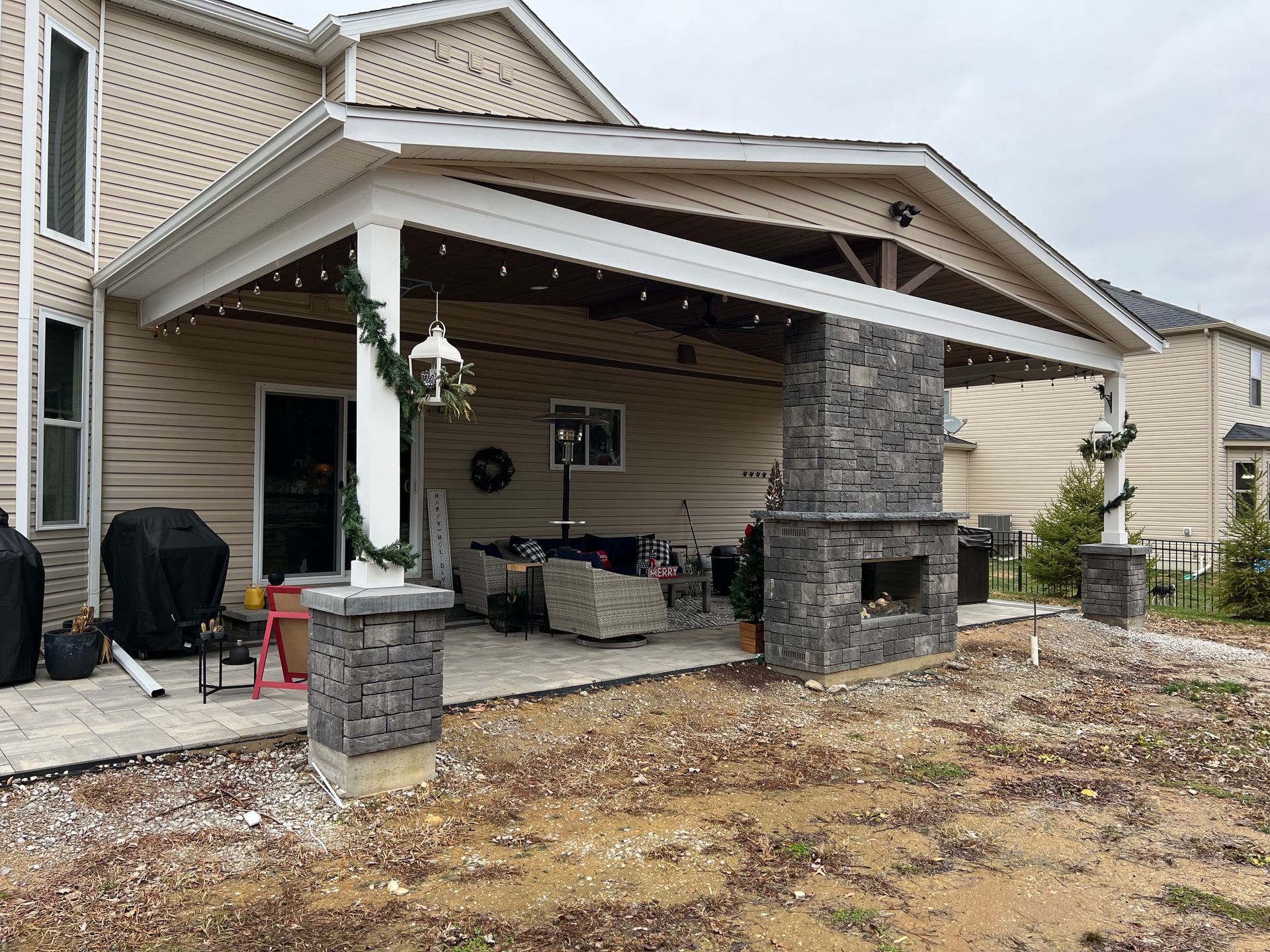 A house with a covered patio and a fireplace in the backyard.